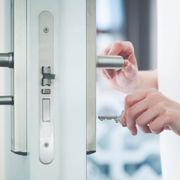 Locking or unlocking modern door with key in hand